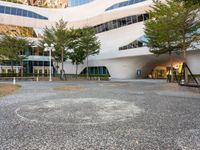 a parking lot with several trees growing in the middle of it and a building on the far corner