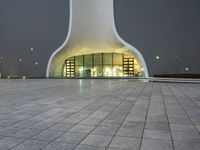 an area with a large dome like structure next to a sidewalk at night with lights