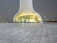 an area with a large dome like structure next to a sidewalk at night with lights