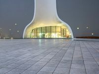 an area with a large dome like structure next to a sidewalk at night with lights