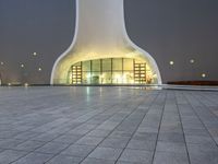 an area with a large dome like structure next to a sidewalk at night with lights