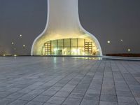 an area with a large dome like structure next to a sidewalk at night with lights