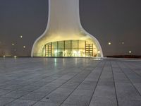 an area with a large dome like structure next to a sidewalk at night with lights