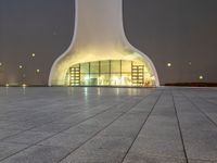 an area with a large dome like structure next to a sidewalk at night with lights