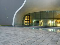 a person is standing by an open air fountain looking at the outside of a building