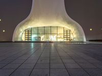 an image of a very modern building at night with lights shining around the outside of it