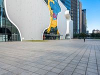 a man walking on the walkway near a large building with art on it's facade