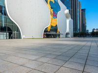 a man walking on the walkway near a large building with art on it's facade