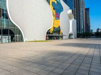 a man walking on the walkway near a large building with art on it's facade