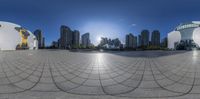 a circle shaped sculpture with buildings in the background and sun on top of it with blue sky