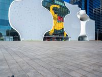 a young man rides a skateboard on a brick sidewalk in front of a glass building