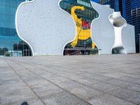 a young man rides a skateboard on a brick sidewalk in front of a glass building