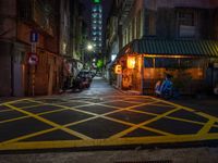 a dark city street with a bicycle parking space on the sidewalk in front of a shop front