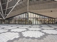 an empty concrete floor of squares in front of a building with large windows and glass