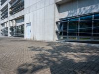 an empty road on a sunny day outside of a building with glass windows and some trees