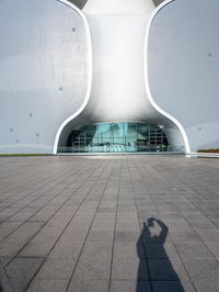 this is a white apple shaped building in a big city with people walking outside it