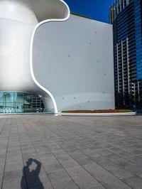 this is a white apple shaped building in a big city with people walking outside it