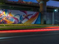 a very nice wall with some very cool artwork in it's background and the light from cars turning around it