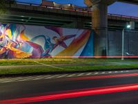 a very nice wall with some very cool artwork in it's background and the light from cars turning around it