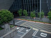 an aerial view of a man waiting to cross the street near buildings and trees in downtown