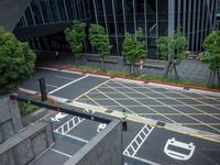 an aerial view of a man waiting to cross the street near buildings and trees in downtown