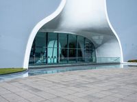 the white curved structure is built into a pool with large windows and plants in it