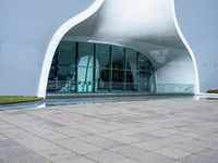 the white curved structure is built into a pool with large windows and plants in it