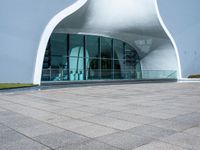 the white curved structure is built into a pool with large windows and plants in it