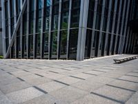 the empty street has long bars of glass around it and benches below it is surrounded by pebbles