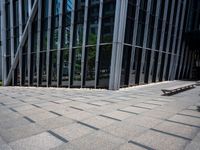 the empty street has long bars of glass around it and benches below it is surrounded by pebbles