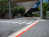 an intersection with the lights on in front of a building and several trees in the back ground