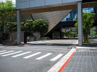 an intersection with the lights on in front of a building and several trees in the back ground