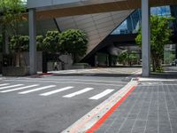 an intersection with the lights on in front of a building and several trees in the back ground