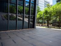 an empty city plaza with trees and benches outside the building that houses an office building