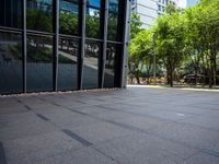 an empty city plaza with trees and benches outside the building that houses an office building