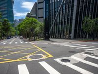 a cross walk on an empty city street, with lots of trees and buildings in the background