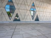 the walkway is surrounded by glass windows in the building and with small triangles around it