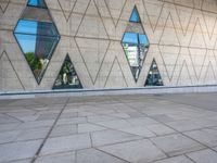 the walkway is surrounded by glass windows in the building and with small triangles around it