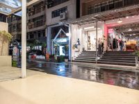 a night view of a building and a store front with rain on the ground,