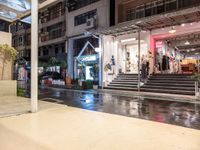 a night view of a building and a store front with rain on the ground,