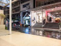 a night view of a building and a store front with rain on the ground,