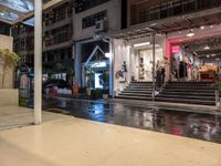 a night view of a building and a store front with rain on the ground,