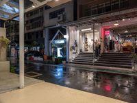 a night view of a building and a store front with rain on the ground,