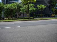 a empty street and two tall buildings next to it with trees lining the sides of it