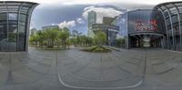 360 - zoom camera image of people's faces and buildings, including glass doors, trees, and green shrubs, all in the foregrounded in the foreground