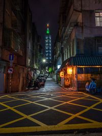 a long narrow street with motor bikes and a tower in the back ground on top of a building