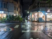 an empty road next to a shopping mall at night at the corner of a crosswalk and a building