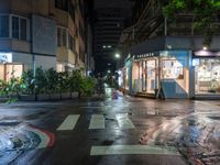 an empty road next to a shopping mall at night at the corner of a crosswalk and a building