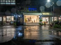 a store front with windows lit up in front and people walking out the front, outside