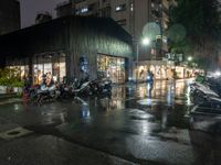 motorcycles parked next to each other on a rainy street corner in front of a building